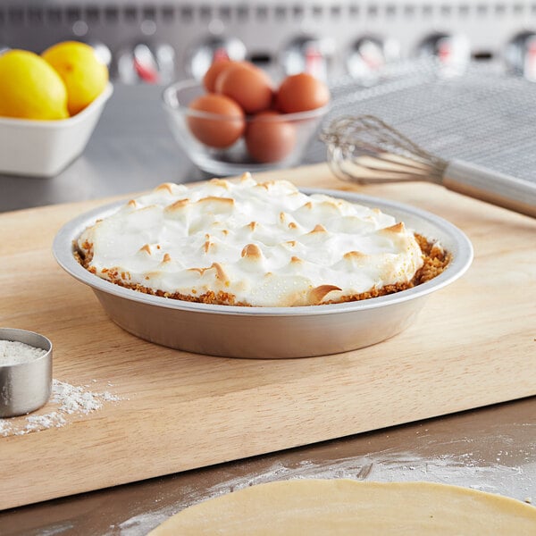 A Baker's Mark deep dish pie with whipped cream on top in a pie pan.