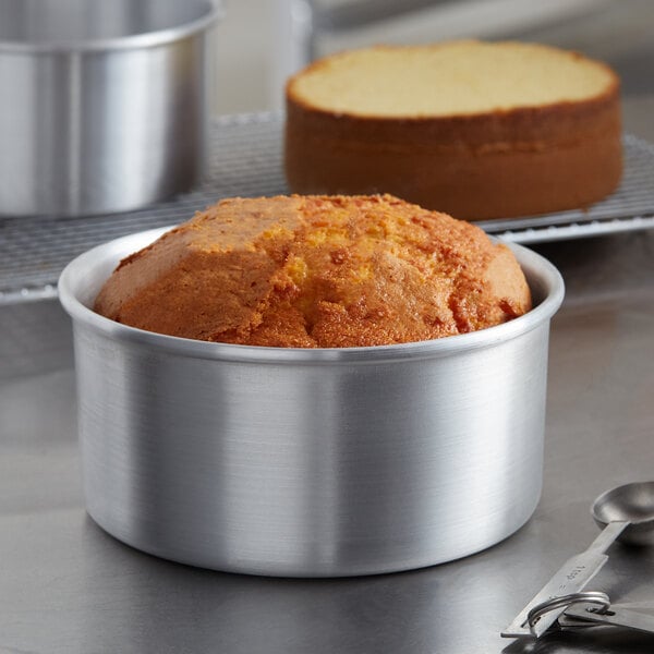 A cake in a Choice round aluminum cake pan on a table in a bakery display.