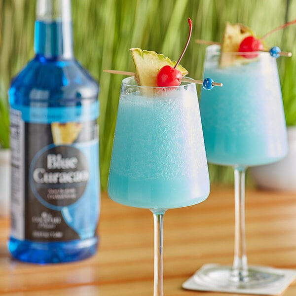 Two glasses of Regal blue curacao with a pineapple garnish on a table in a cocktail bar.