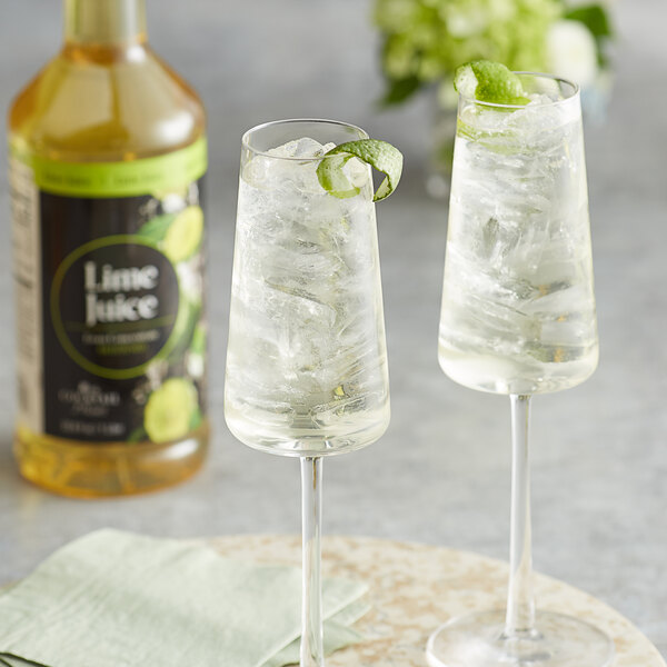 A bottle of Regal Cocktail Lime Juice with two glasses of lime juice with ice and lime slices.