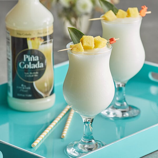 Two glasses of white Pina Colada with pineapple slices on top.