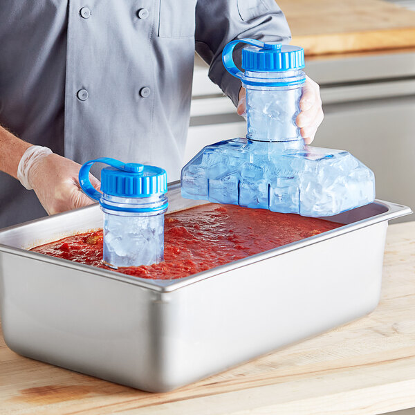 A man using two blue Vigor Polar Paddles to cool red sauce in a pan.
