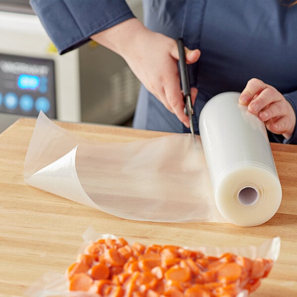 A hand cutting a roll of Choice Full Mesh External Vacuum Packaging Bags.