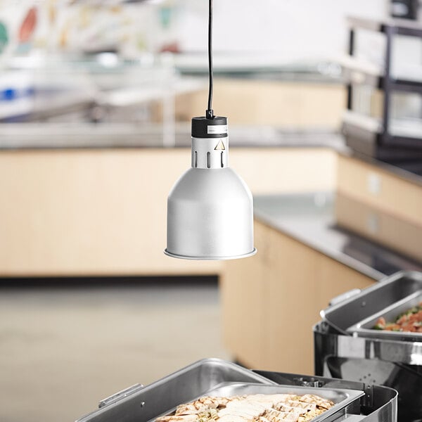A ServIt ceiling mount heat lamp with a flared round dome shade hanging over a buffet table with trays of food.