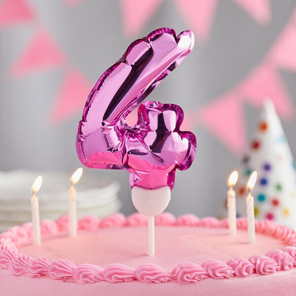 A pink cake with a balloon shaped number four on top.