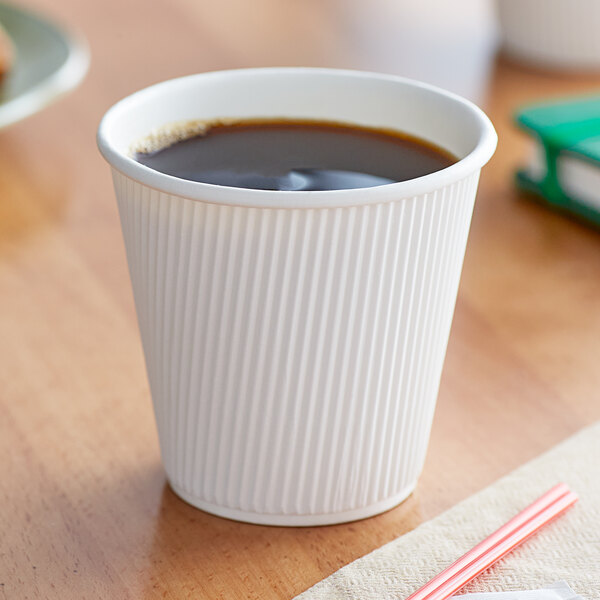 A Choice white double wall paper hot cup filled with coffee on a table.
