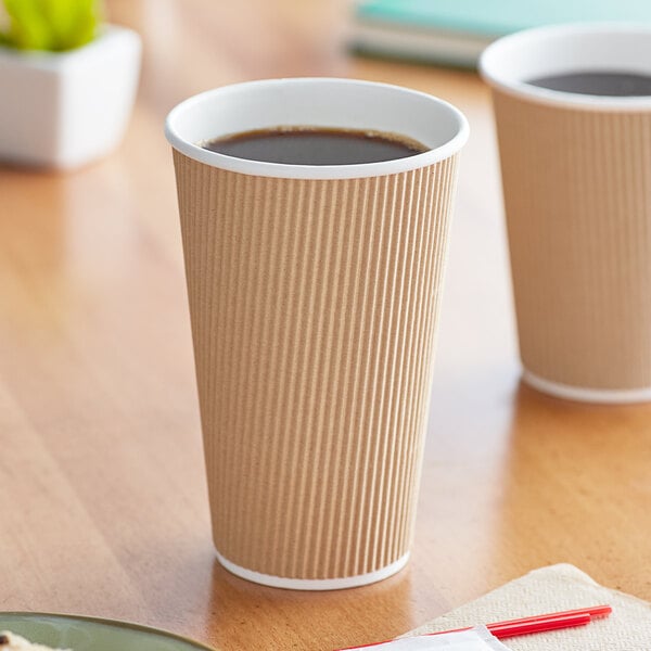 A table with two brown Choice paper cups filled with coffee.