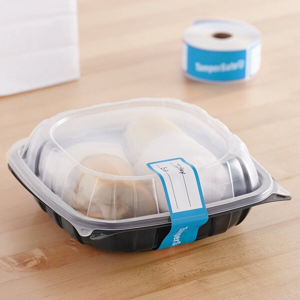 A plastic container with a roll of blue paper labels.