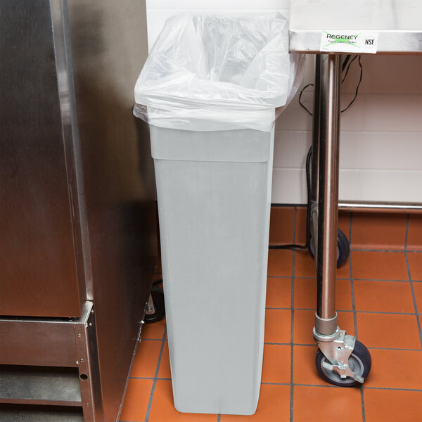 A gray Continental rectangular wall hugger trash can with a bag over it.