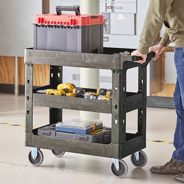 A man holding a black Lavex utility cart with tools.