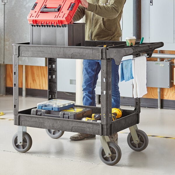 A man standing next to a Lavex black utility cart with tools in it.