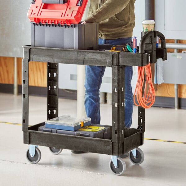 A man standing with a Lavex utility cart full of tools and a toolbox.