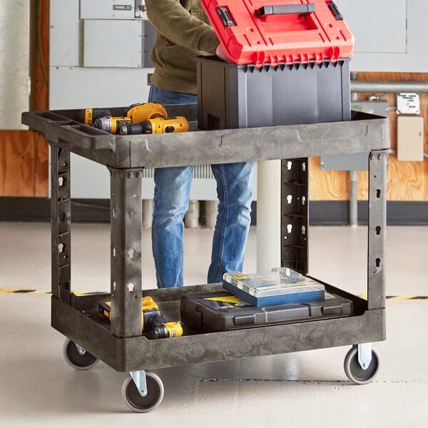 A man standing next to a Lavex black utility cart with a red tool box on it.