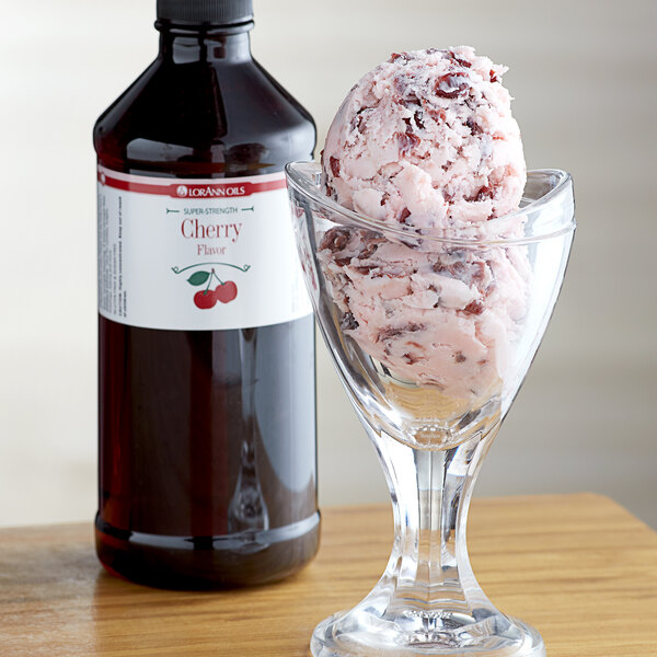 A glass of ice cream with a scoop of cherry syrup on top next to a bottle of LorAnn Oils Cherry Super Strength Flavor.