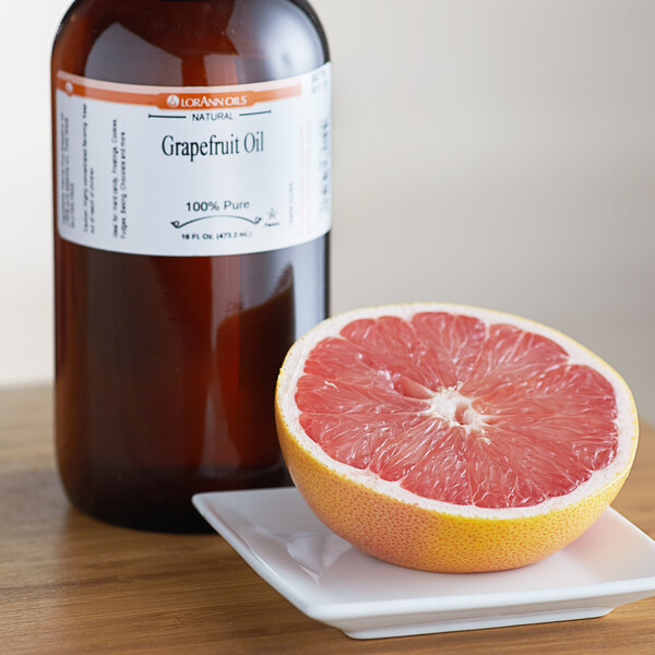 A grapefruit sits on a plate next to a bottle of LorAnn Oils grapefruit flavor.