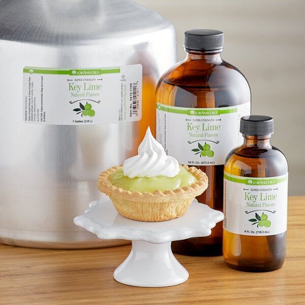 A bottle of LorAnn Oils All-Natural Key Lime Super Strength Flavor on a table with a pie and whipped cream.