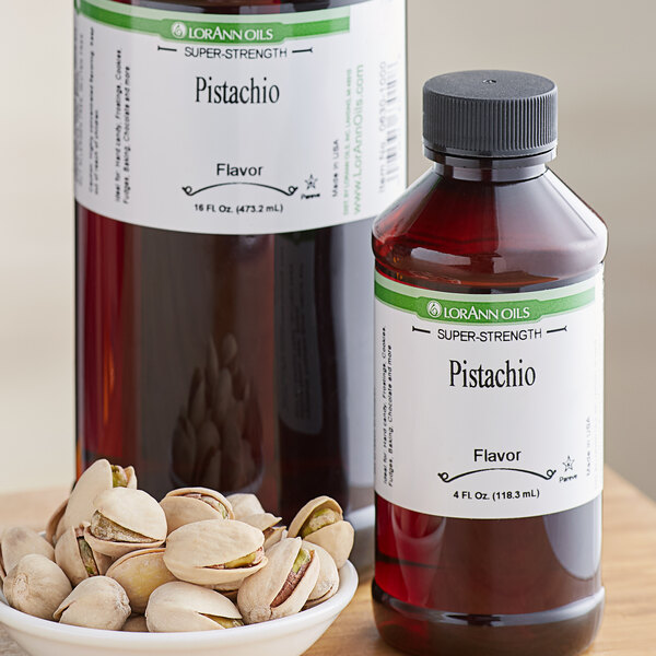 A bottle of LorAnn Oils Pistachio Super Strength Flavor next to a bowl of pistachios on a counter.