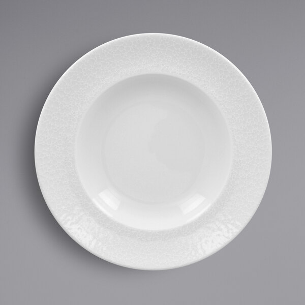 A close-up of a RAK Porcelain white porcelain plate with a textured white rim.