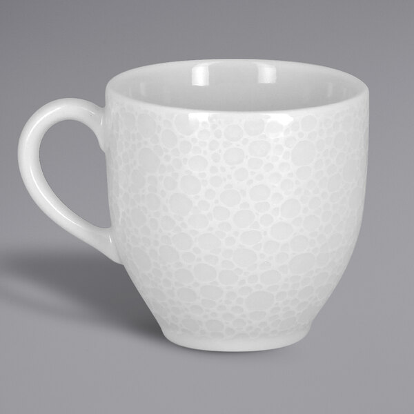 A white RAK Porcelain espresso cup with an embossed pattern and a handle.