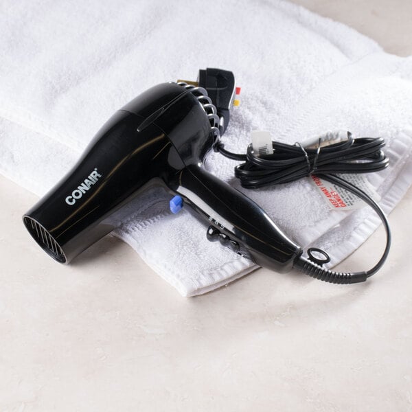 A Conair black hair dryer on a towel.