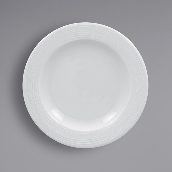 A white RAK Porcelain wide rim porcelain plate with spiral lines.