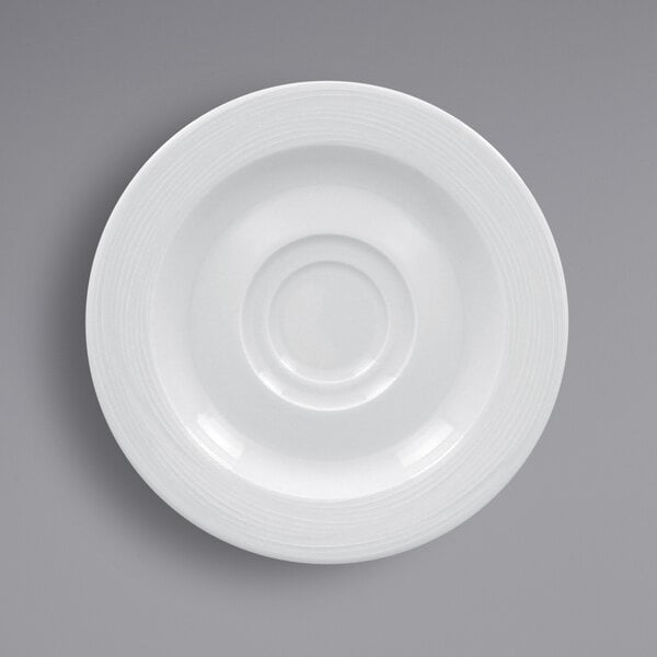 A close-up of a RAK Porcelain bright white saucer with a circular design.