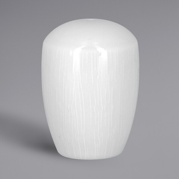 A white vase with an embossed design and a lid on a gray surface.