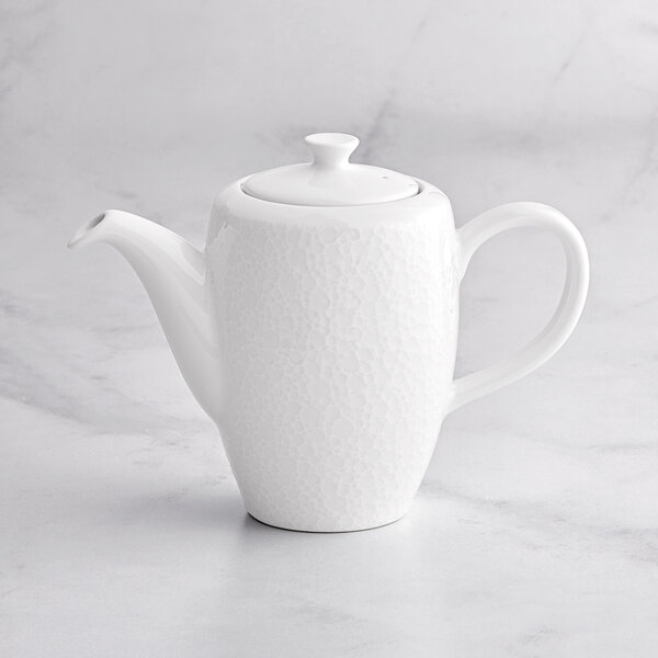 A white RAK Porcelain coffee pot with a lid on a marble surface.