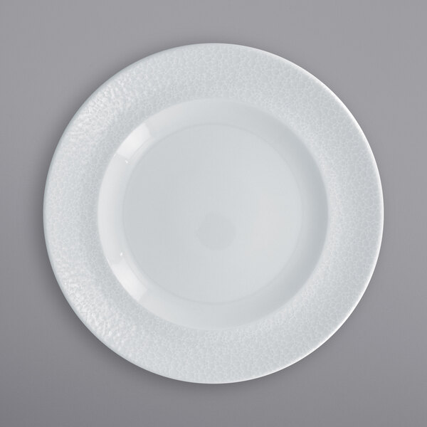A close-up of a RAK Porcelain white plate with a small amount of food on it.