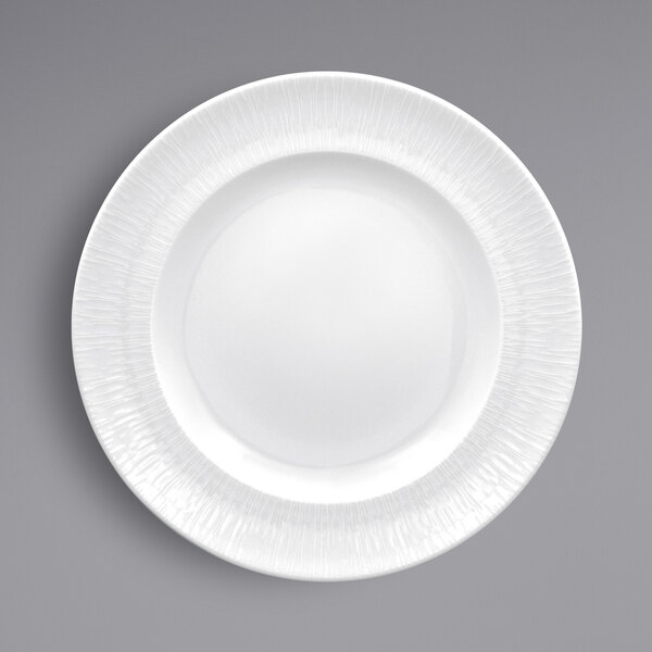 A close-up of a RAK Porcelain white porcelain plate with a textured rim.