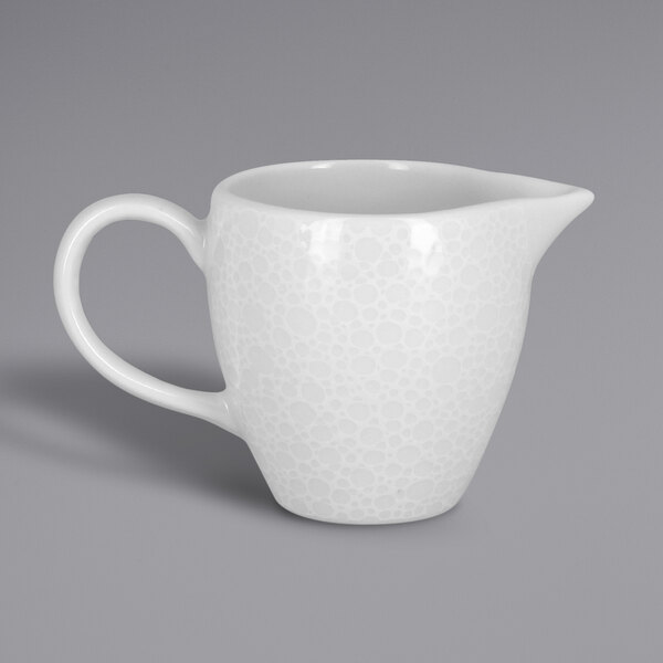 A RAK Porcelain bright white creamer with an embossed design and a handle.