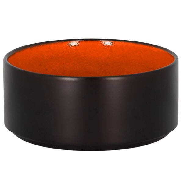 A black bowl with an orange rim with the RAK Porcelain logo on the bottom.