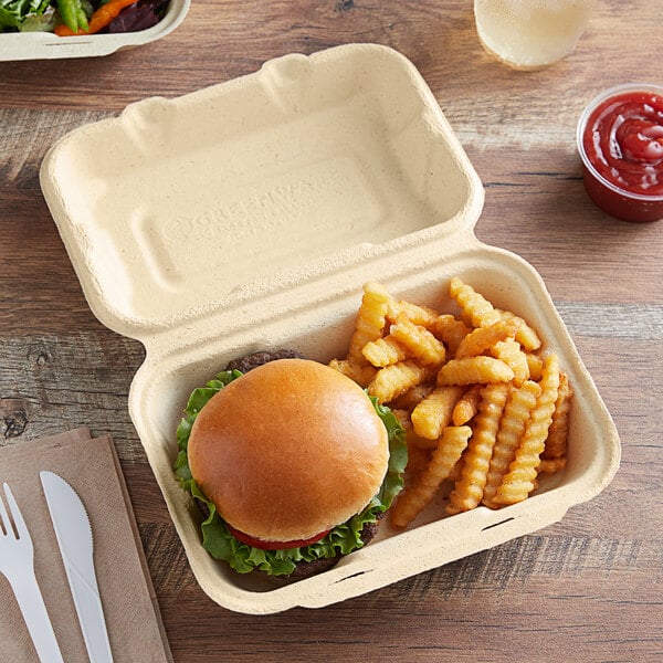 A Fabri-Kal Greenware hinged container with a burger and fries inside.