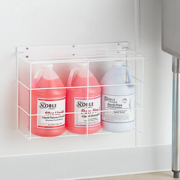 A white metal Dema rack holding three gallon bottles of liquid, including a pink and white Dema bottle.