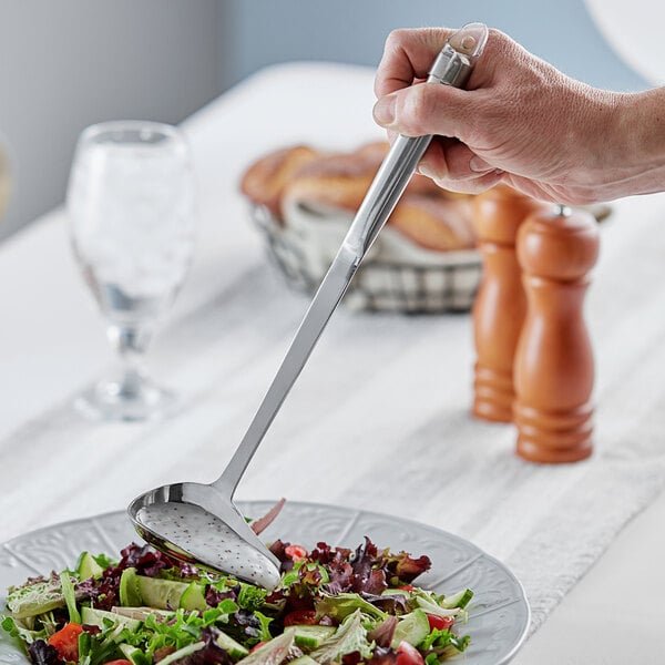 A person using a Choice stainless steel pour spout ladle to serve salad at a salad bar.