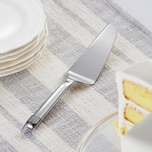 A Choice stainless steel cake server next to a plate with a slice of cake on it.