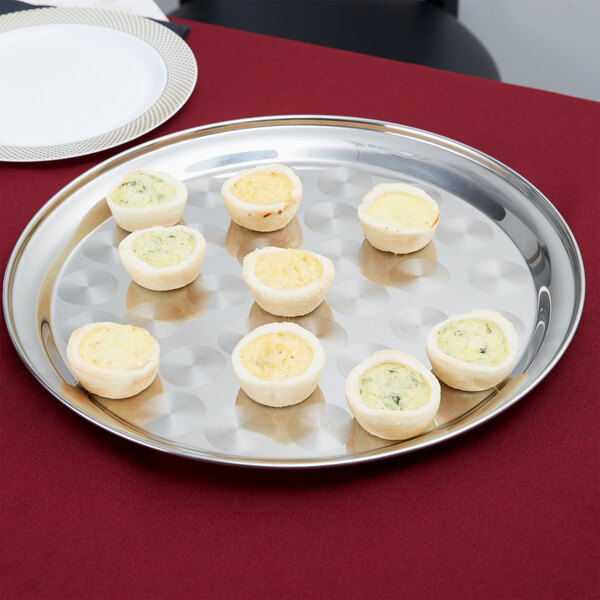 A Thunder Group stainless steel serving tray with a swirl pattern holding mini quiches.
