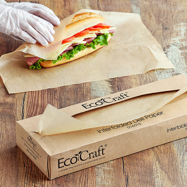 A person in white gloves putting a sandwich in an EcoCraft deli wrapper.
