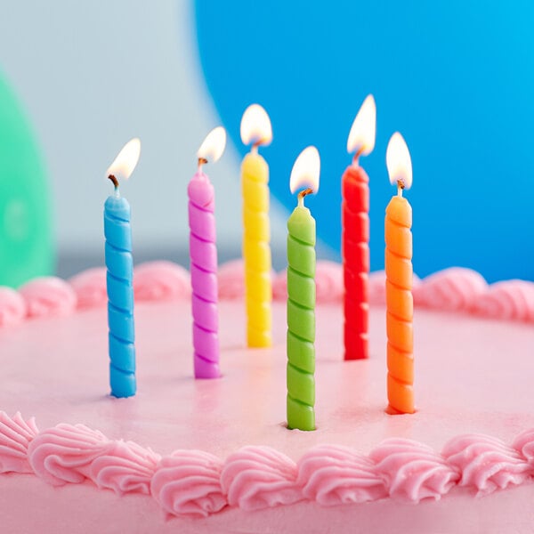 A birthday cake with rainbow spiral candles on it.