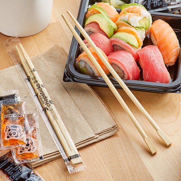 A tray of sushi with Emperor's Select bamboo chopsticks on a table.