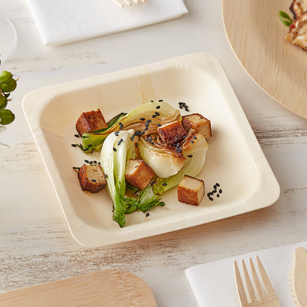 A TreeVive by EcoChoice compostable wooden square plate with food on it and a wooden fork on a napkin.