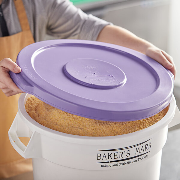 A woman holding a purple lid on top of a large white container.