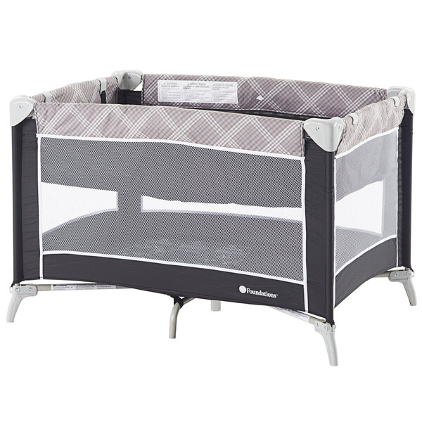 A Foundations Sleep 'N' Store playard with a graphite and grey plaid bassinet and mesh cover.