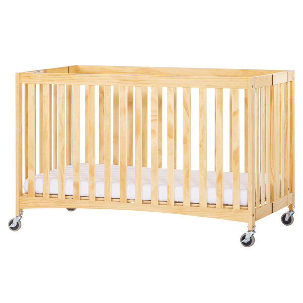 A wooden crib with wheels and a white sheet.
