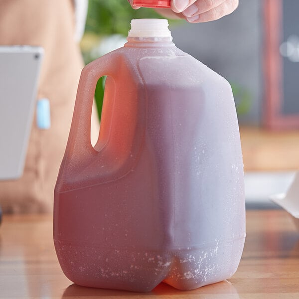 A hand pouring liquid from a Translucent HDPE Jug into another jug.