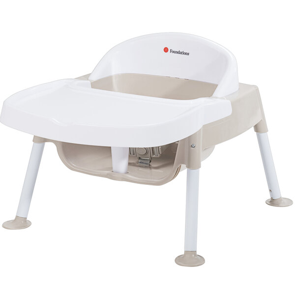 A white baby feeding chair with tan accents.