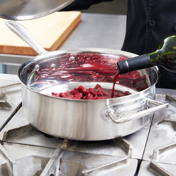 A person pouring red wine into a Vollrath saute pan.