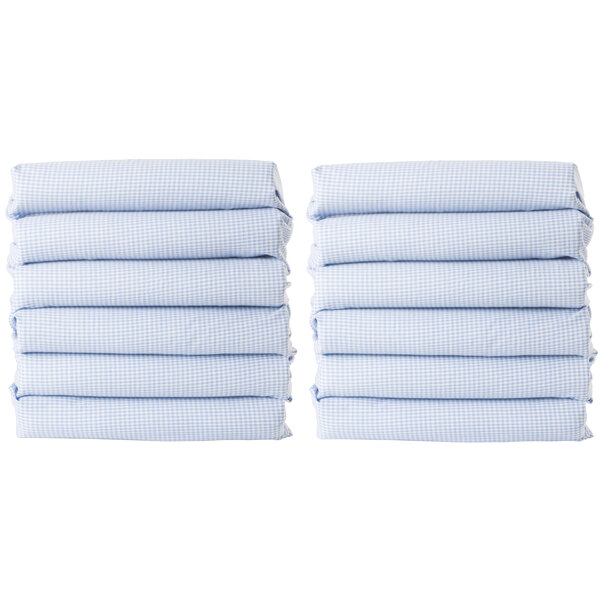A stack of six blue gingham Foundations CozyFit cot sheets.