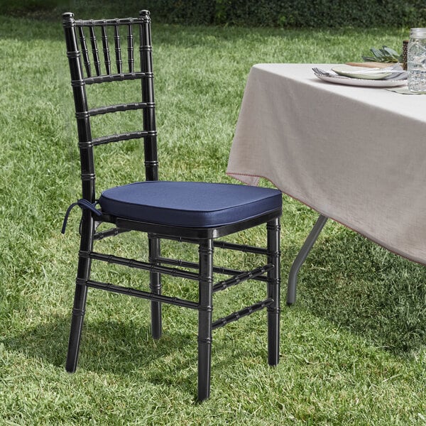 A Lancaster Table & Seating black Chiavari chair with a navy blue cushion on a table
