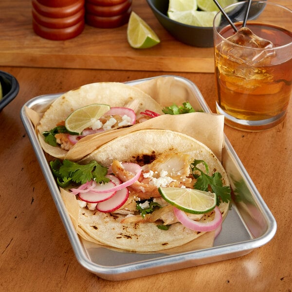 A Baker's Mark aluminum bun pan with two tacos and a drink on it.